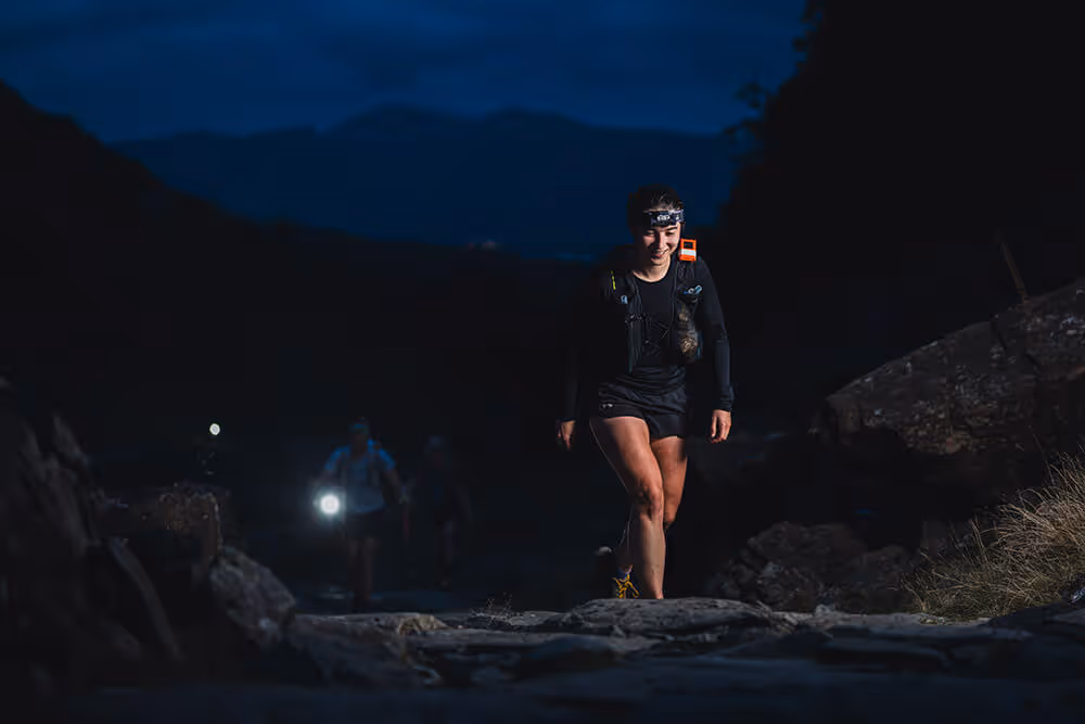 Image shows a lone female runner wearing a head torch in the dark